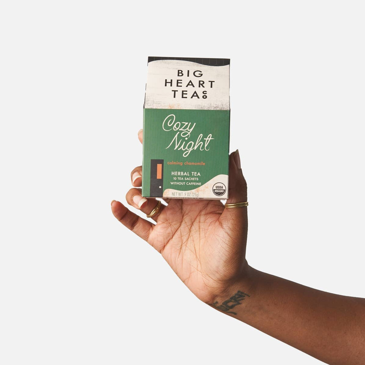 Hand holding a package of Big Heart Teas Cozy Night tea against a white background