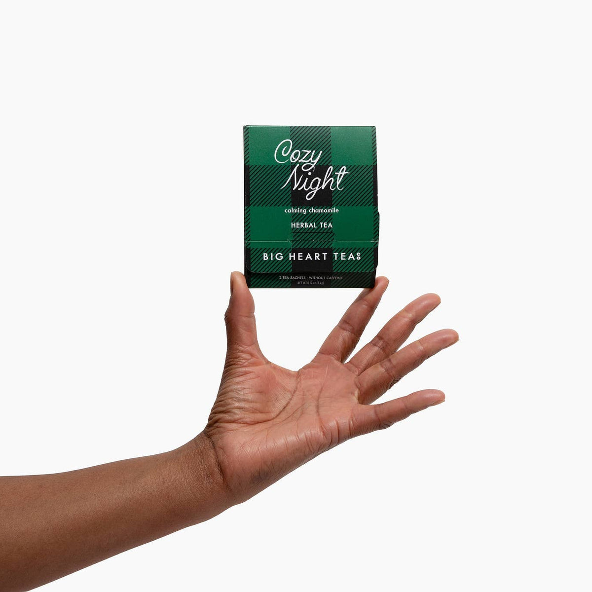 Hand holding a green tea box labeled 'Cozy Night' against a white background