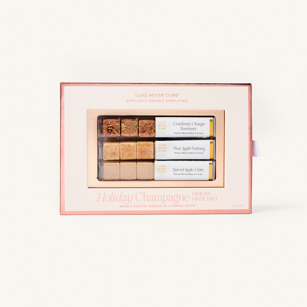 A boxed set of three sugar cube cocktail mixers  labeled 'Holiday Champagne,' shown in its pink and white packaging against a clean white background.