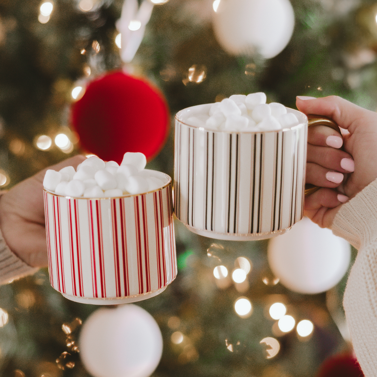 Two mugs. One in Red Stripes and One with Green Stripes with White Background and Gold Handles. 
