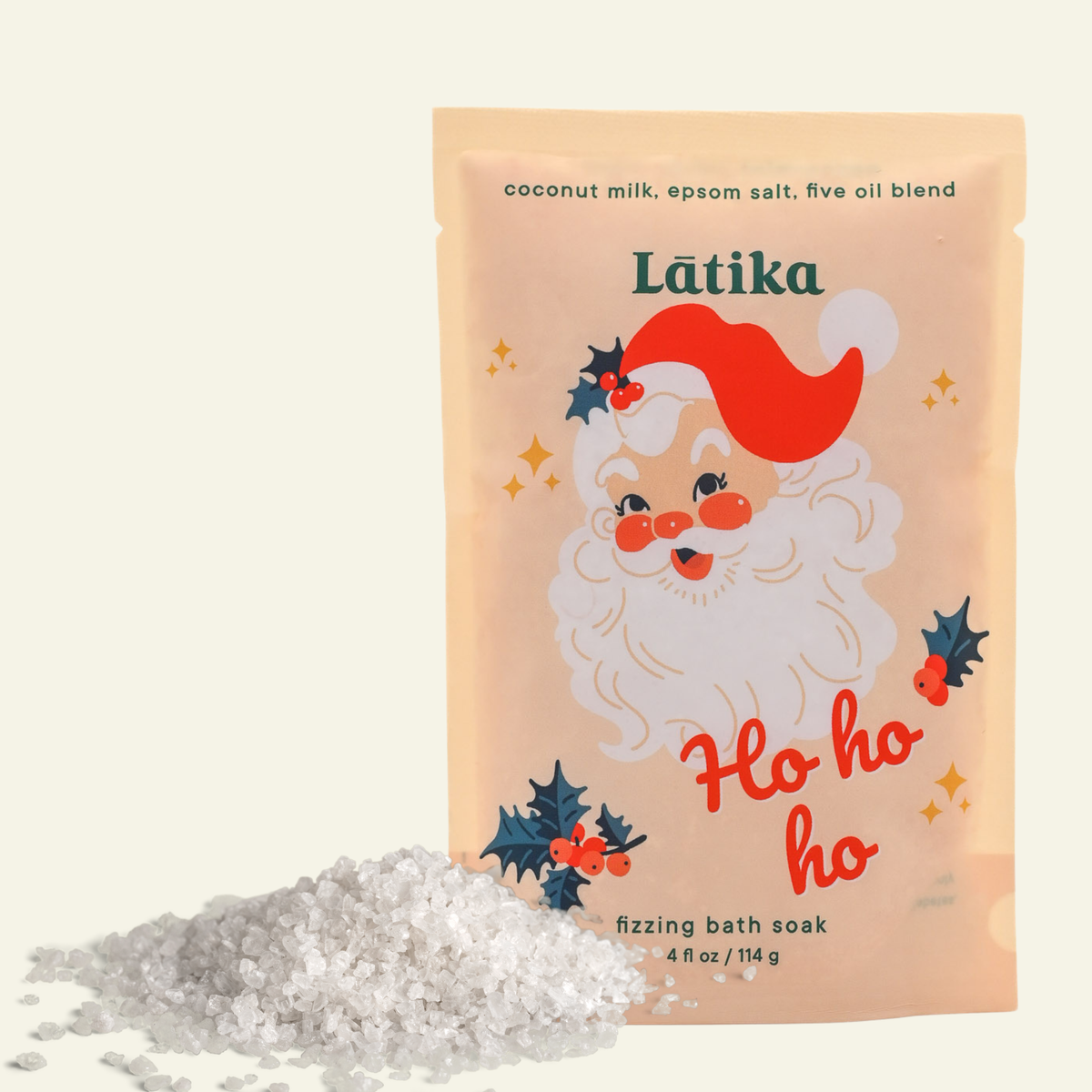 A stand-up pouch of Latika 'Ho ho ho' fizzing bath soak with a pile of white bath salts in front, on a light cream background.