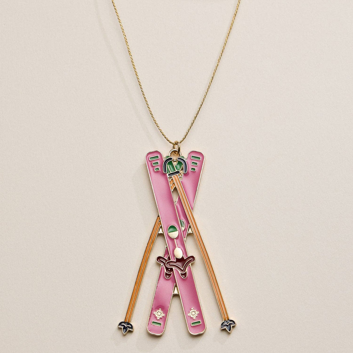 Ornament with pink skis and ski poles pendant on a beige background