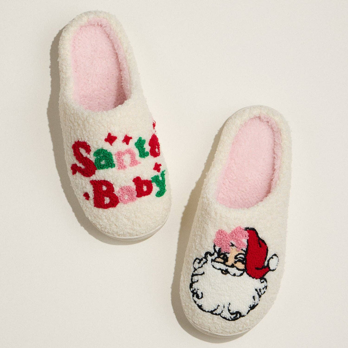 Pair of slippers with 'Santa Baby' text and a cartoon Santa face on a light background