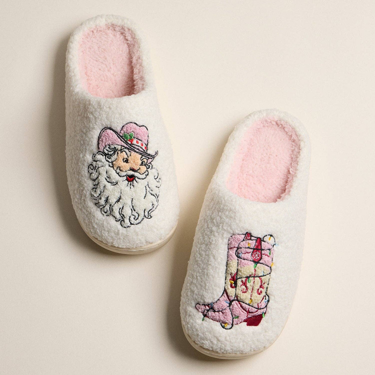 Pair of slippers with embroidered designs of Santa and Cowgirl Boots on a beige background